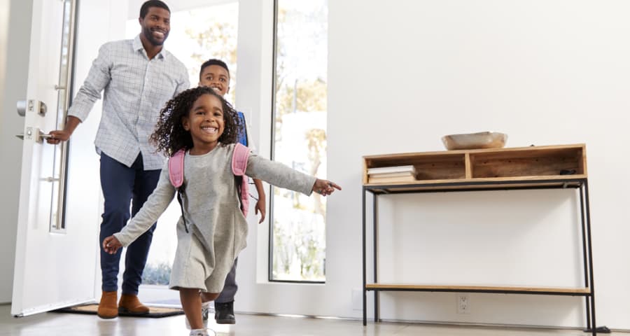 Father and children entering through the front door of their home